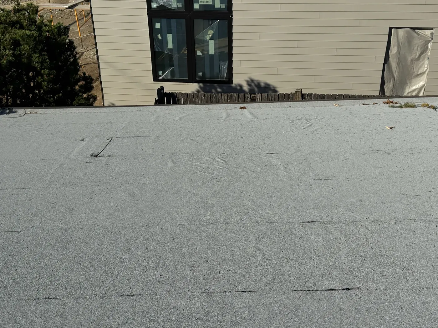 Crew adhering new membrane sheets across the flat roof