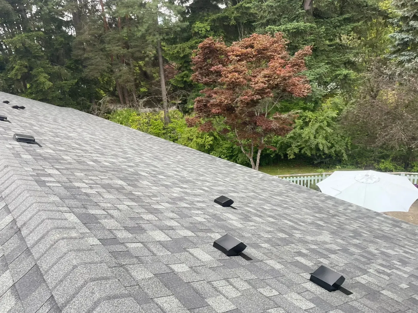 Completed light gray architectural shingle roof seen from the ridge line