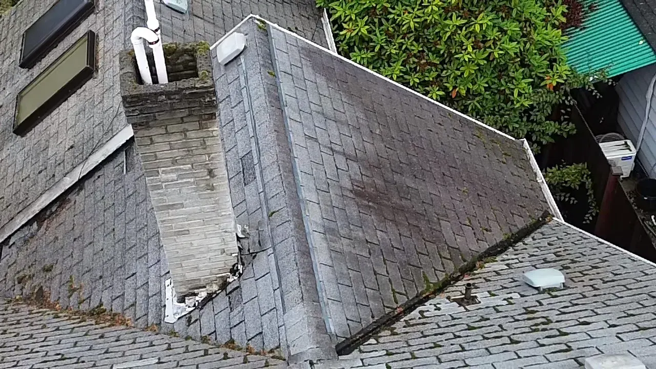 Aging shingle roof with moss, rusted flashing and widespread wear nearing end of life